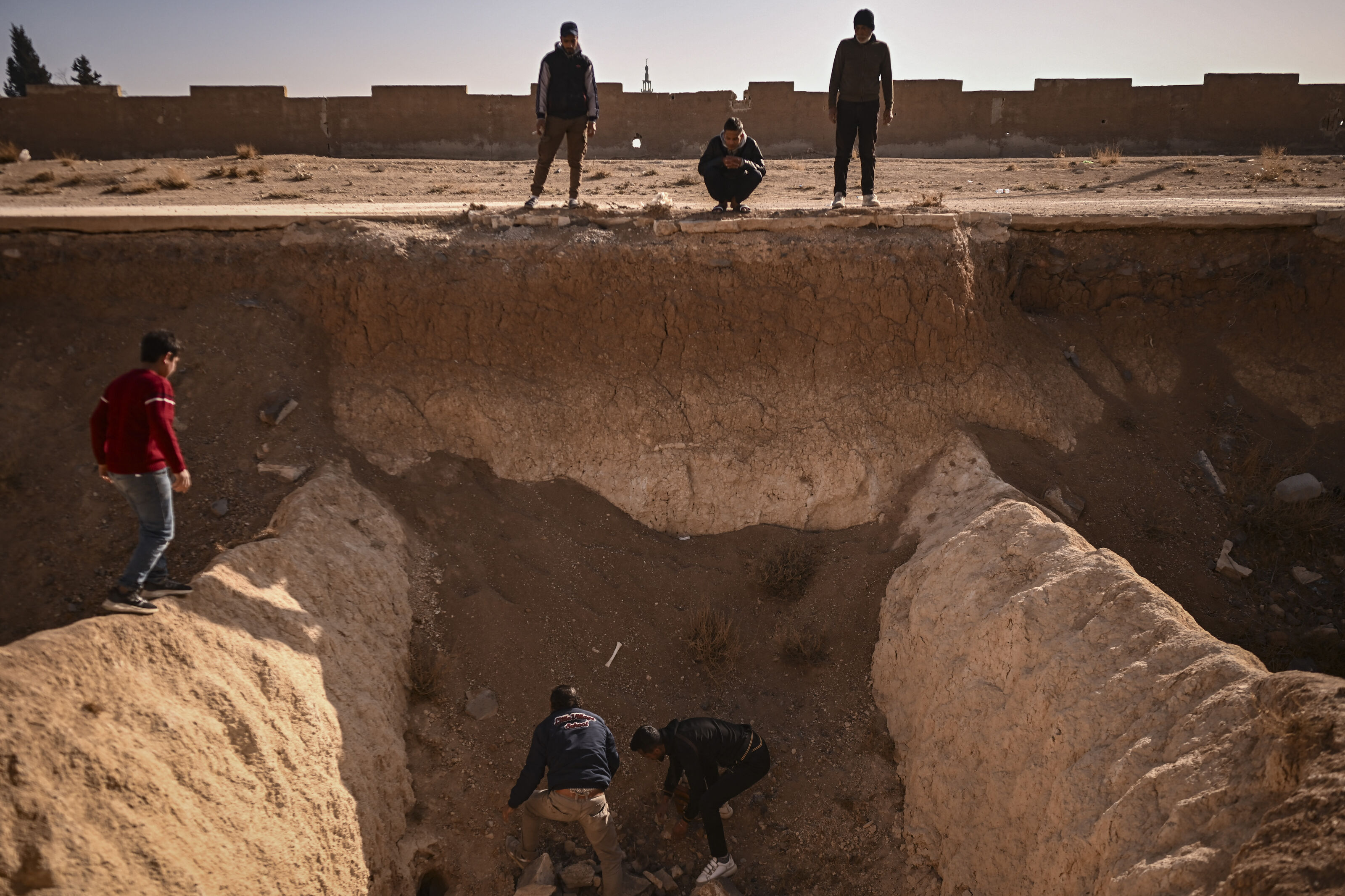 People search for human remains at a trench believed to be used as a mass grave on the outskirts of Damascus on December 16, 2024.
