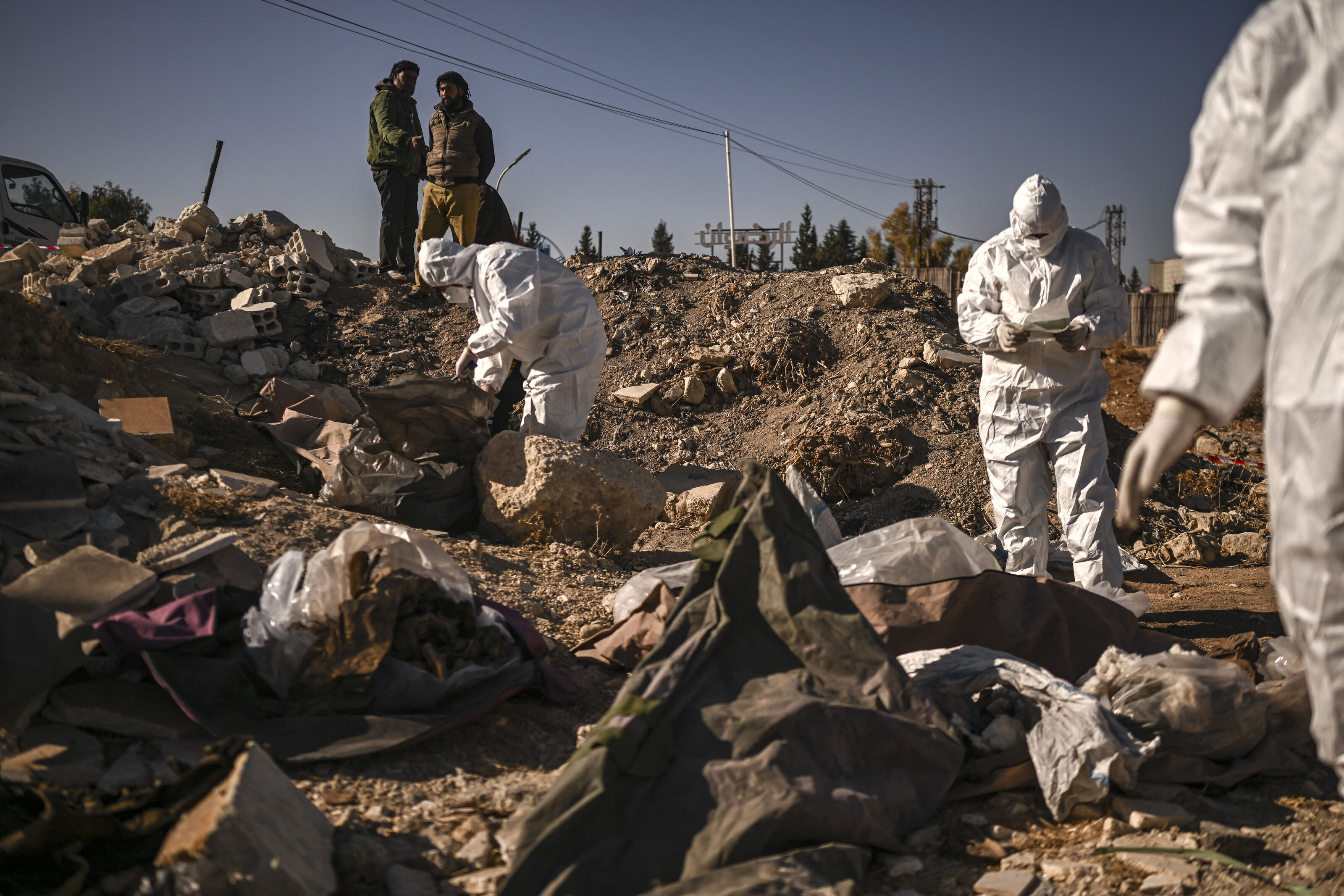 Members of Syria's White Helmets civil defence collect human remains at a mass grave that was uncovered, in Damascus, on December 16, 2024. 