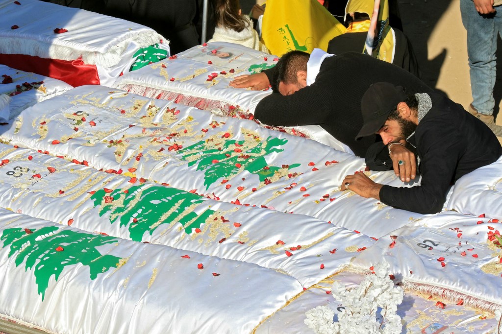 People mourn over the flag-draped coffins of loved ones during the funeral on February 28, 2025 of 95 people killed in Israeli air strikes in the southern Lebanese border town of Aitaroun.&nbsp;