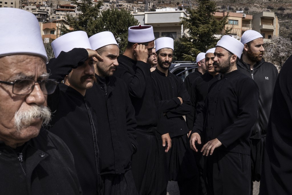Druze men stand near a border barrier in the village of Majdal Shams, in the Israeli-occupied Golan Heights, as they wait for buses transporting visiting Druze men from Syria, on March 14, 2025. (AFP)