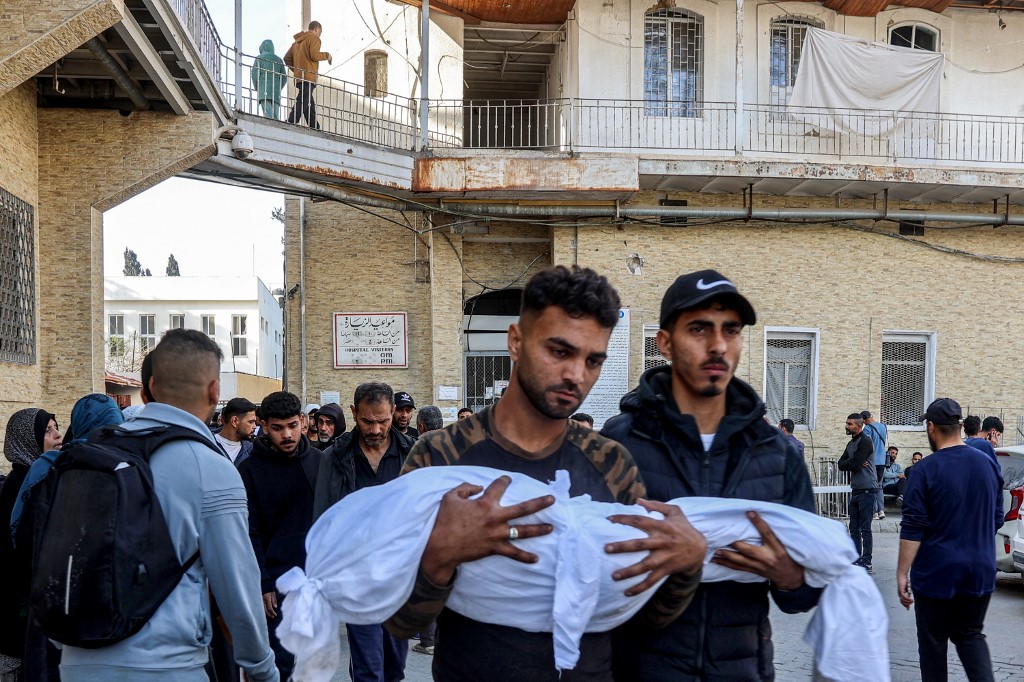 Men walk carrying the shrouded bodies of young victims who were killed in Israeli bombardment in Gaza City, at the Ahli Arab hospital, also known as the Baptist hospital, in Gaza City on March 18, 2025. (AFP)