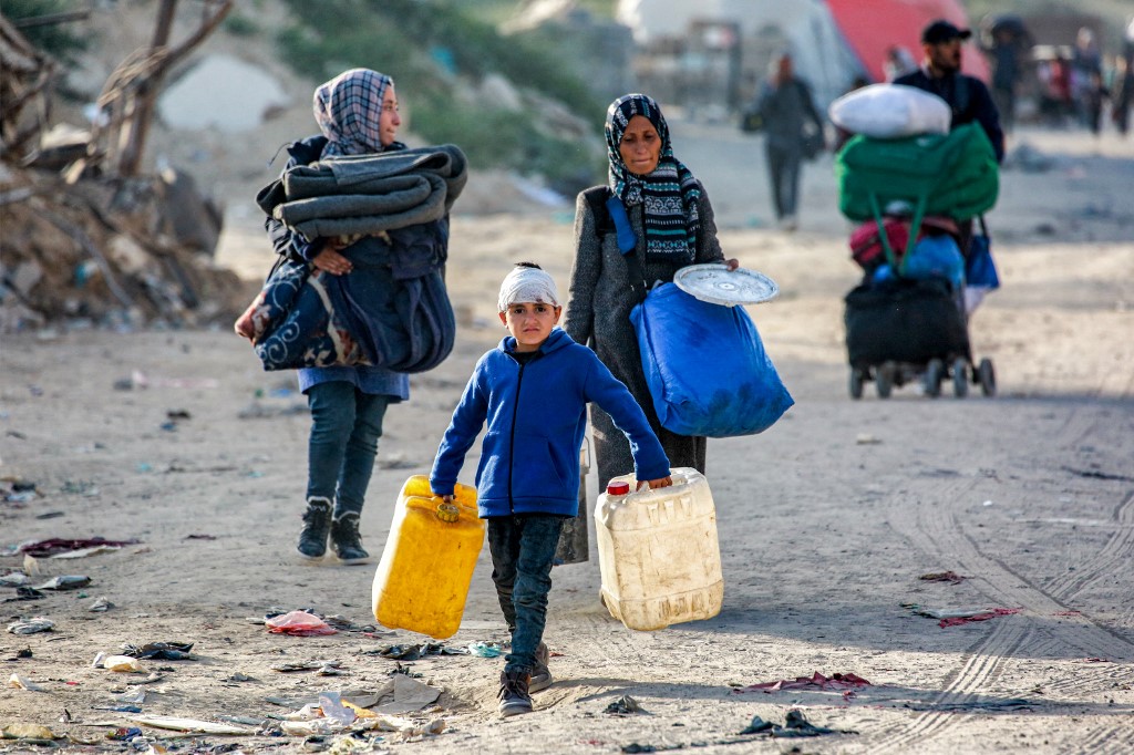 A boy walks with empty jerrycans as people displaced by Israel’s renewed war on Gaza and fleeing from Beit Hanun in the northern Gaza Strip arrive in Gaza City on March 18, 2025. (Bashar Taleb/AFP)