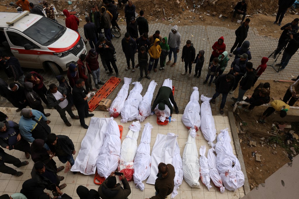 Palestinians gather near the bodies of the victims of Israeli overnight air strikes in the northern Gaza Strip, in front of the Indonesian Hospital in Beit Lahia on March 20, 2025. (AFP)