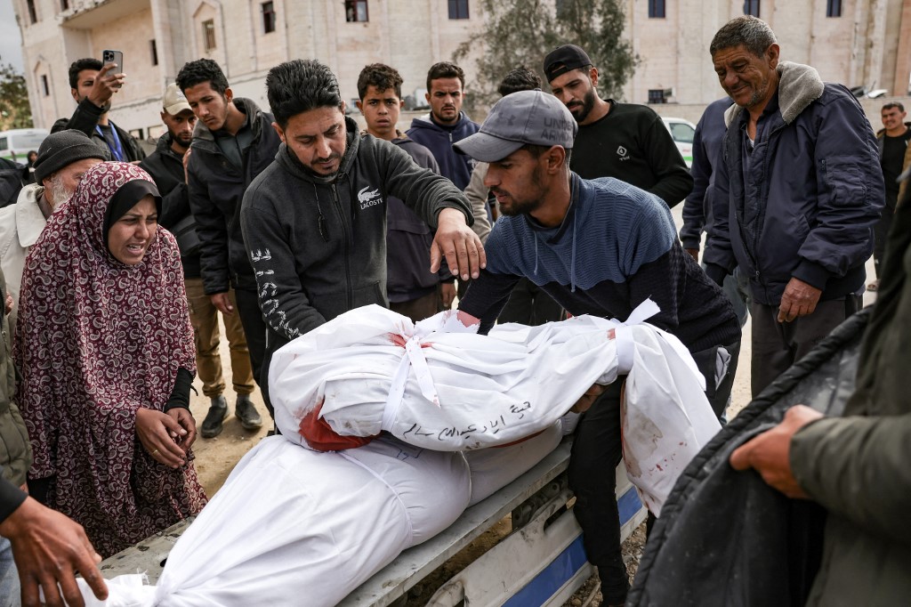 A Palestinian man places the body of a child killed in an Israeli strike on top of that of a family member in Beit Lahia in the northern Gaza Strip on 22 March 2025 (Bashar Taleb/AFP)