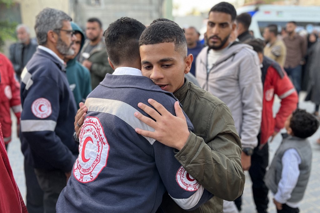 A paramedic embraces a youth&nbsp;outside Nasser Medical Complex in Khan Yunis in the southern Gaza Strip on 30 March, 2025 as the bodies of Palestinian first responders arrive at the facility. (AFP)