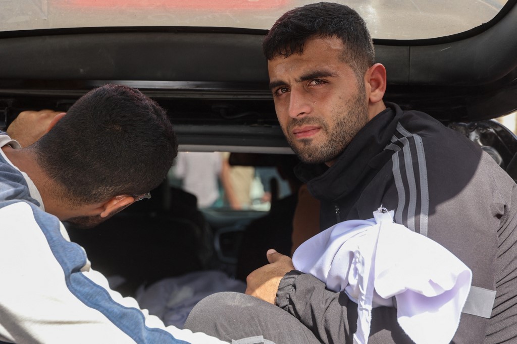 A man carries the cloth-wrapped body of a baby killed in an Israeli strike on northern Gaza, at the Ahli Arab Hospital in Gaza City on 3 April, 2025. (AFP)