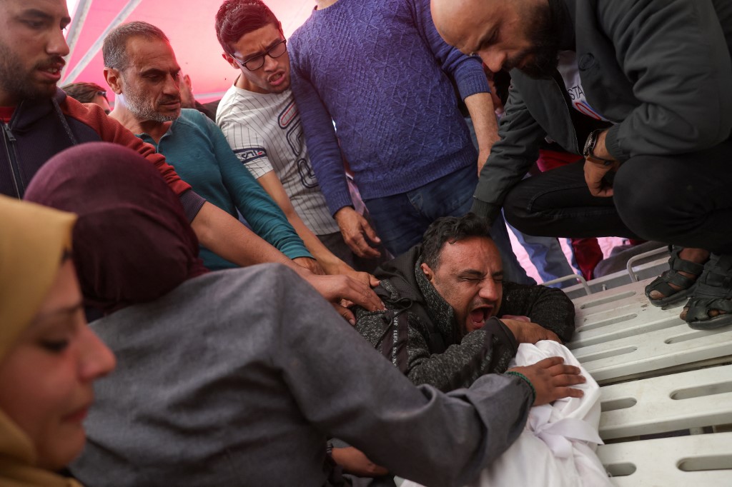 The father of Abir Srour mourns over the shrouded body of his daughter, killed in an Israeli strike, during her funeral at the Indonesian Hospital in Beit Lahia in the northern Gaza Strip on April 17, 2025. (AFP)