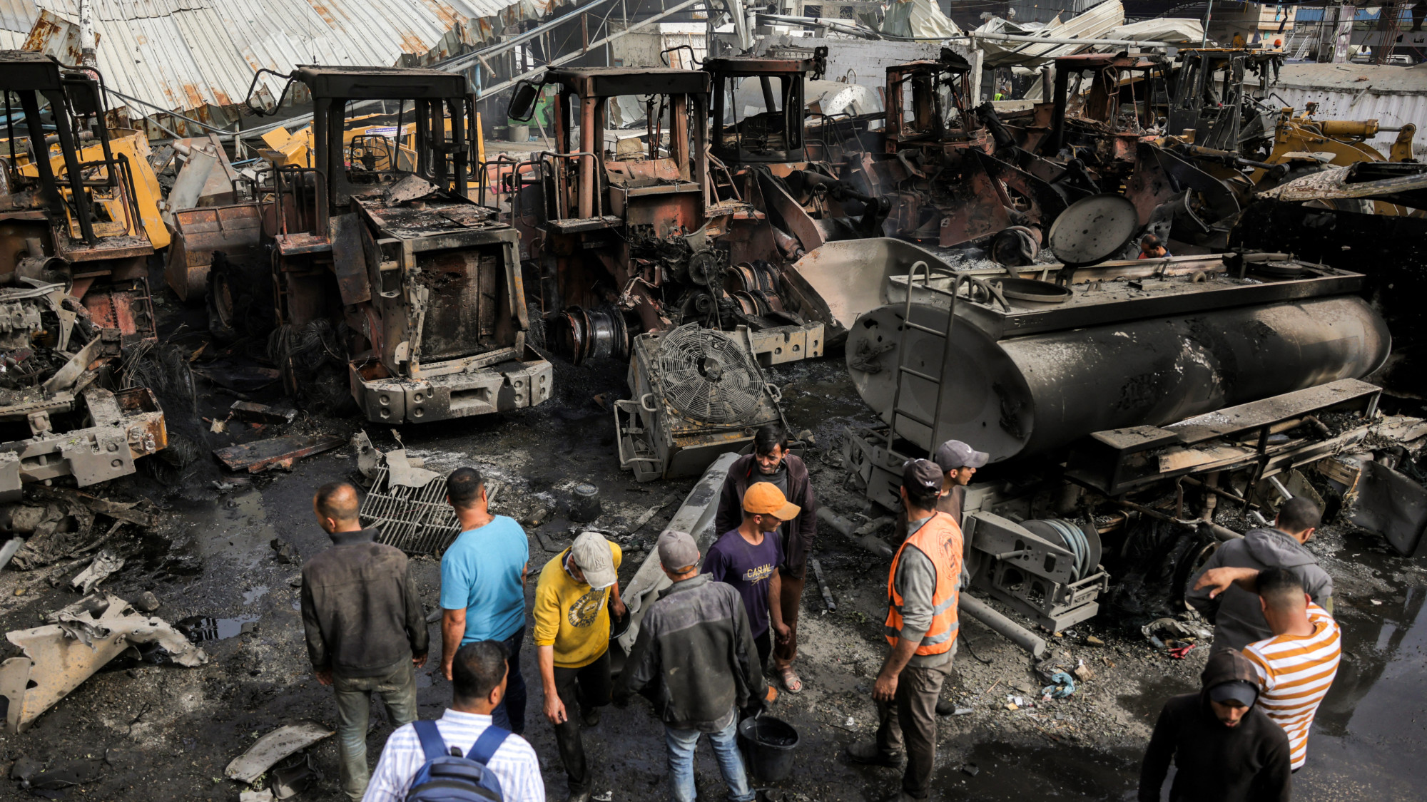 Men inspect destroyed bulldozers and other vehicles following the Israeli attack on the the Jabalia municipality garage (AFP/Basahr Taleb)