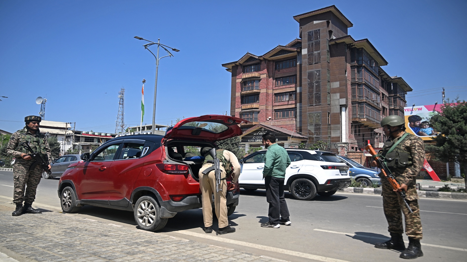 Indian paramilitary troopers stand guard as a policeman searches the car of a commuter along a street in Srinagar on 30 April 2025 (Tauseef Mustafa/AFP)