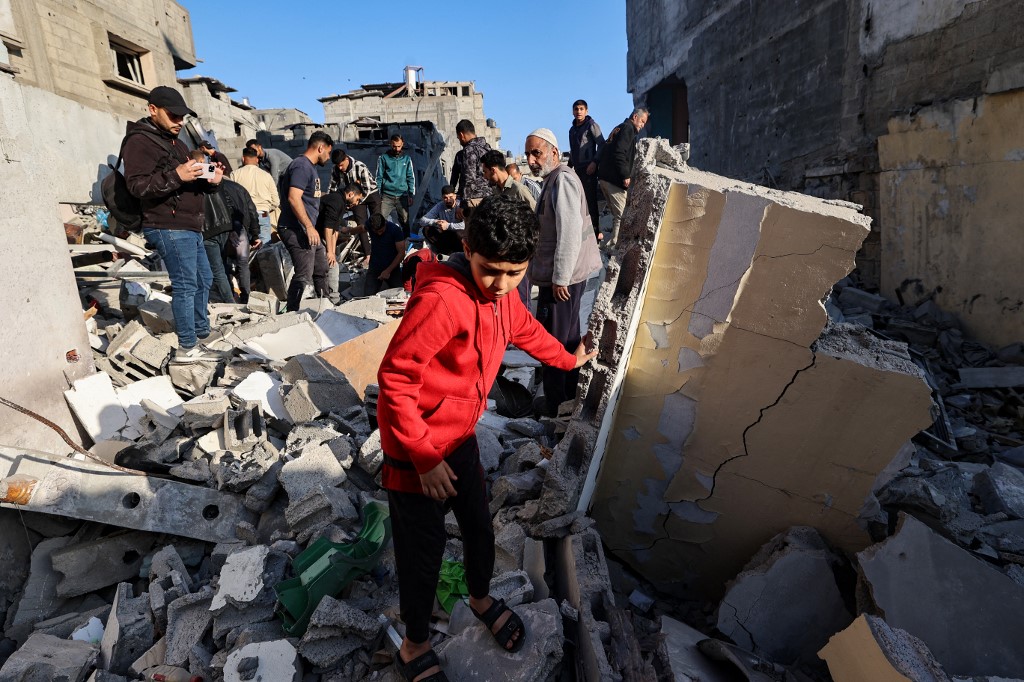 A child looks on as people look for survivors in the rubble of a building hit in an Israeli strike in the Bureij camp for Palestinian refugees in the central Gaza Strip on 2 May, 2025. (AFP)