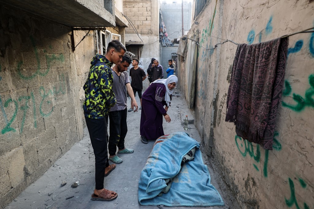People stand over the shrouded body of a person killed in an Israeli strike that hit a building in the Bureij camp for Palestinian refugees in the central Gaza Strip on May 2, 2025. (AFP)