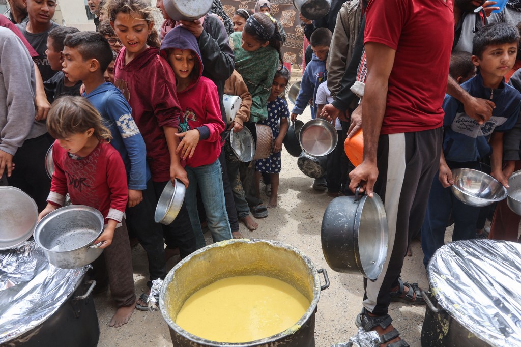 Palestinians shove to get a ration of hot food from a charity kitchen set up at the Islamic University campus in Gaza City on May 12, 2025.