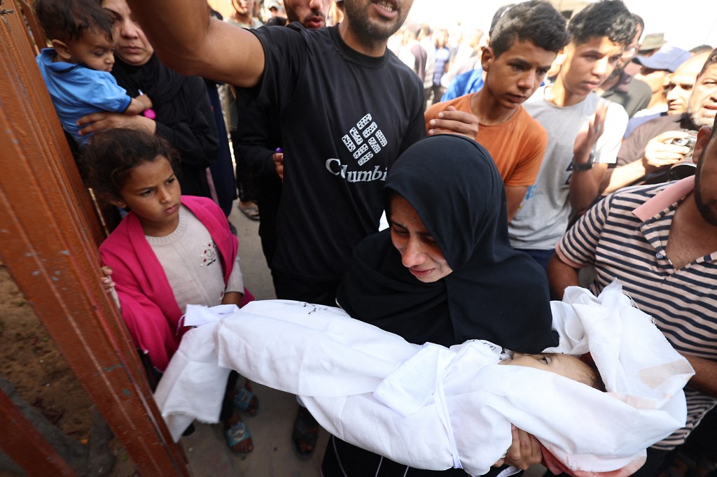 A woman holds the body of a baby ahead of a funeral procession of victims of an Israeli strike in Khan Yunis in the southern Gaza Strip, on May 14, 2025.