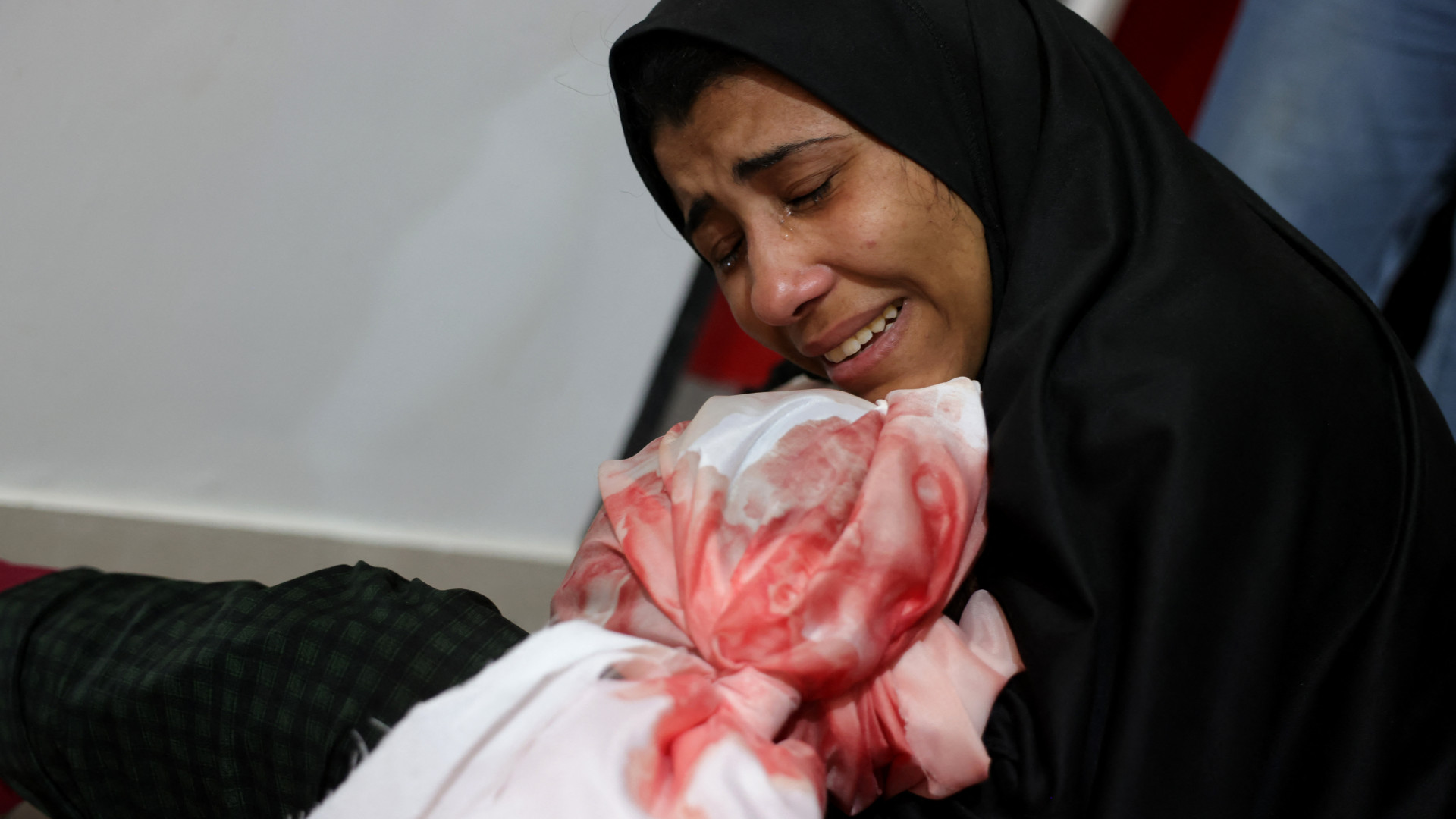 A Palestinian woman cries as she holds the body of a child killed in Israeli strikes on Jabalia, at the Indonesian Hospital in Beit Lahia in the northern Gaza Strip on May 14, 2025 (Bashar Taleb/AFP)