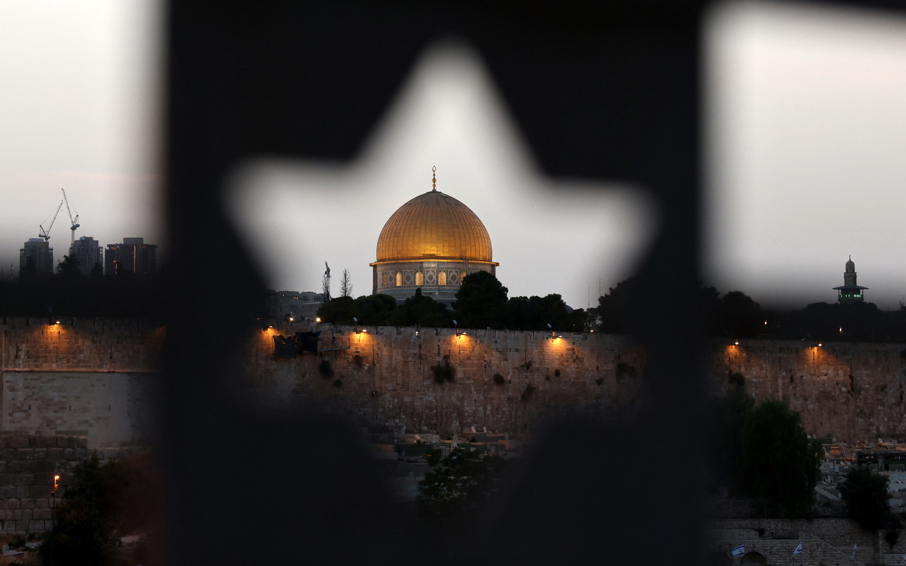 This picture taken from the Mount of Olives through a gate decorated with the Star of David, shows a partial view of Jerusalem's Old City and the Dome of the Rock in mosque, on May 17, 2025.