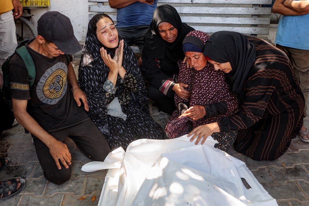 Women mourn by the body of a person who was killed following reported Israeli attacks on aid queues in the Sudaniya area in northwestern Gaza, at Al-Shifa hospital in Gaza City on June 14, 2025.