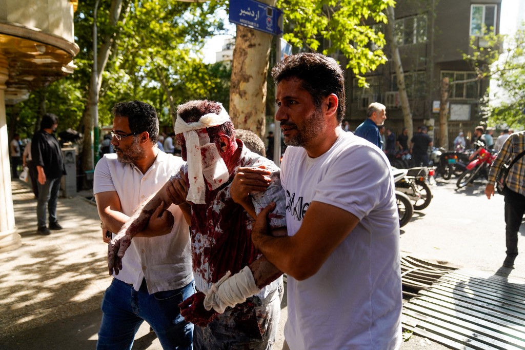 Iranians care for a man who was injured in a reported Israeli strike on Keshavarz Boulevard in downtown Tehran on June 15, 2025. 