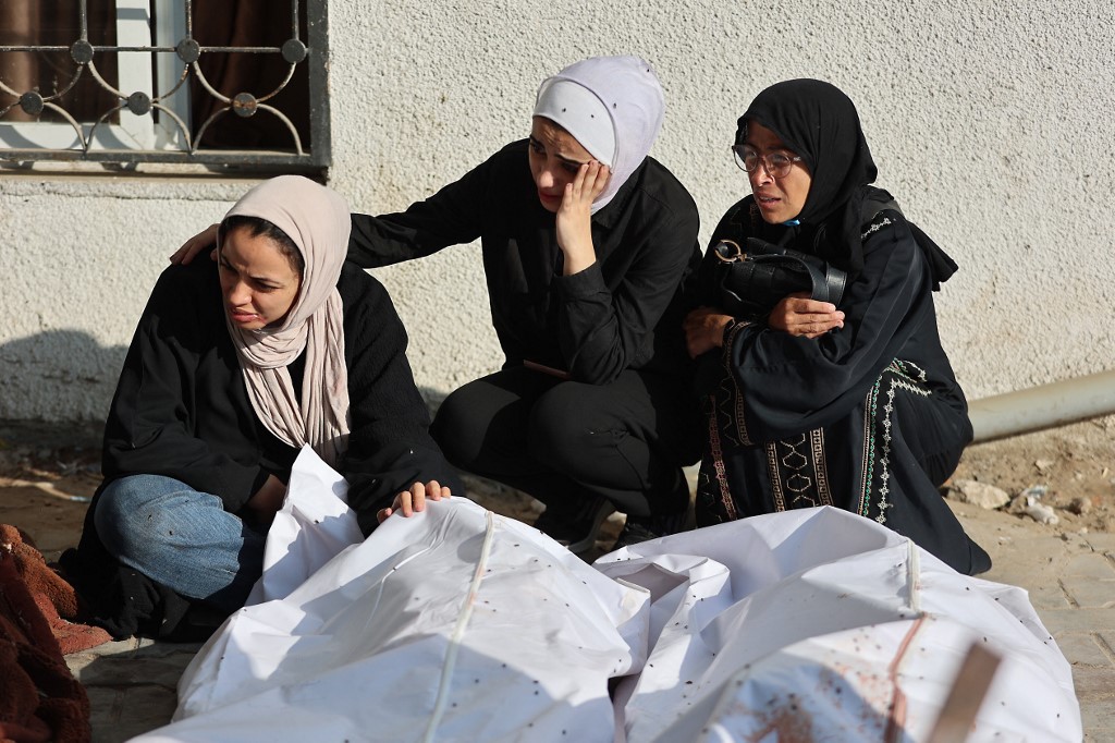 Palestinian women mourn the death of loved ones, killed during overnight Israeli strikes, outside the morgue of Al-Shifa hospital in Gaza City on June 26, 2025, 