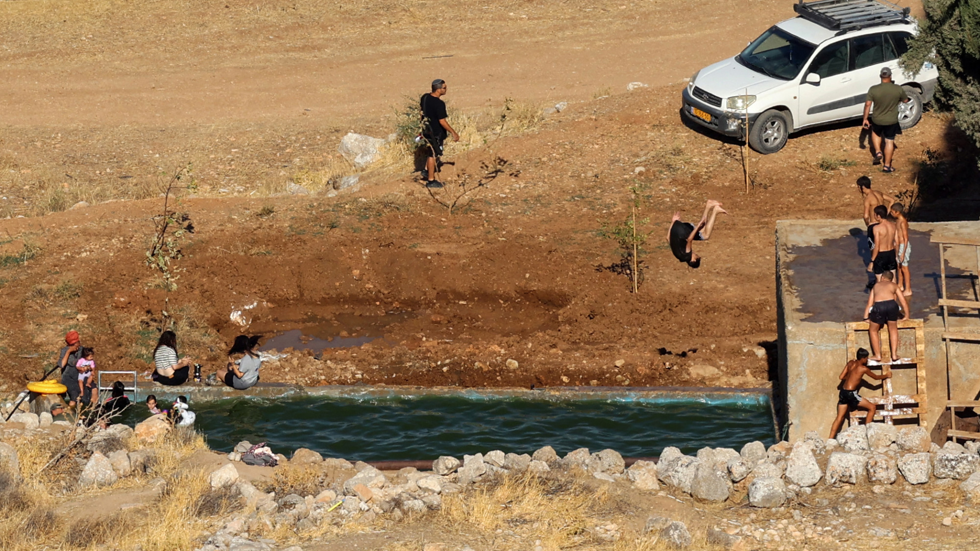 Israeli settlers swim in the Ein Samiyah spring near the village of Kafr Malik, in the occupied West Bank, on 15 July 2025 (AFP/Zain Jaafar)