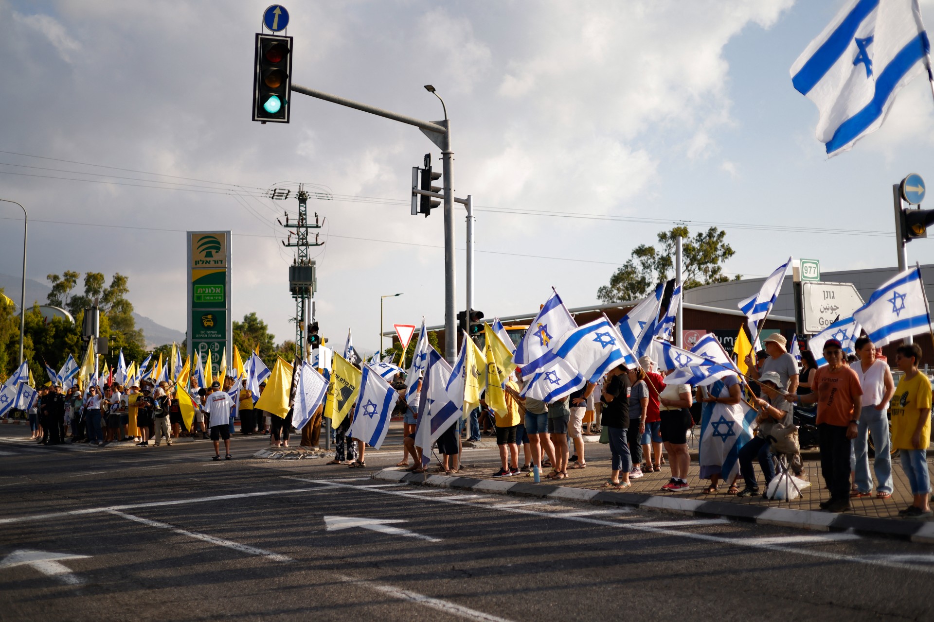 Israelis wave national and yellow flags in Kiryat Shmona as they protest against their government demanding a deal to release Israeli captives in Gaza (AFP/Jalaa Marey)