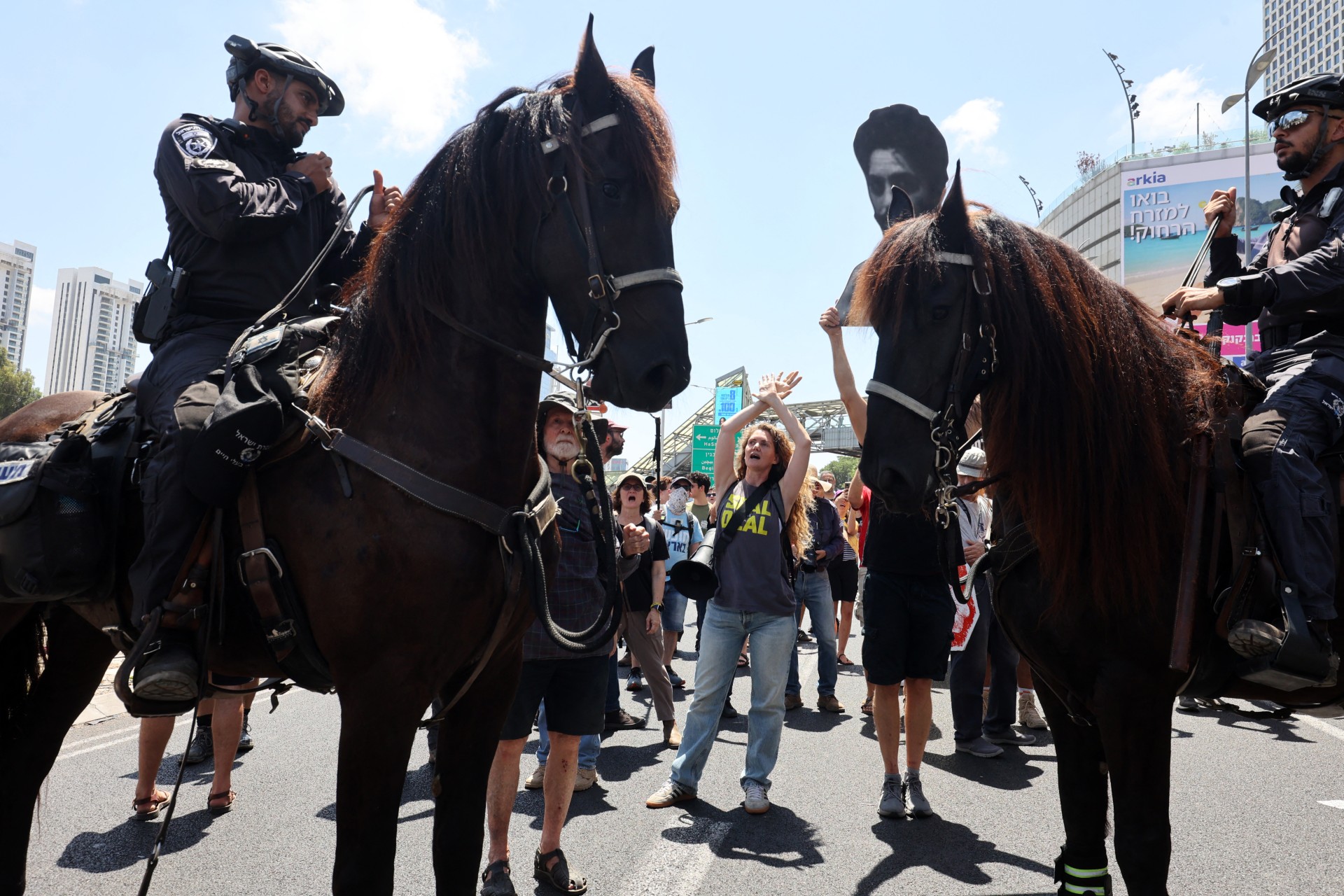 A demonstrator shouts slogans in front of mounted Israeli policemen at a protest in Tel Aviv on 17 August 2025 (AFP/Gil Cohen-Magen)