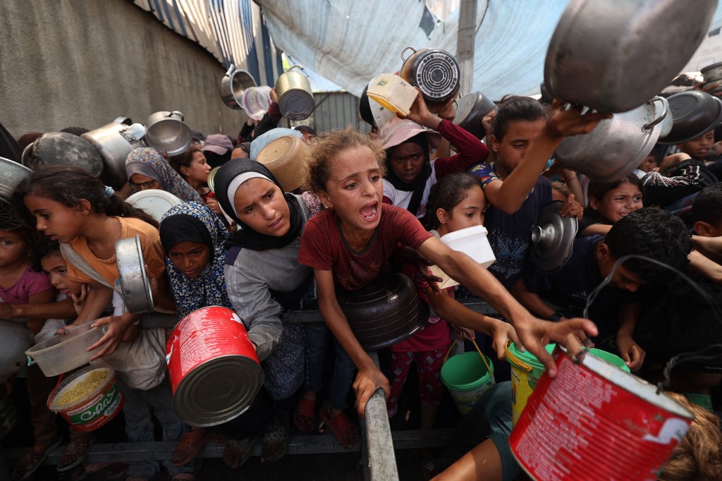 Palestinians gather to receive cooked meals from a food distribution center in the Nuseirat refugee camp in the central Gaza Strip on August 18, 2025. 