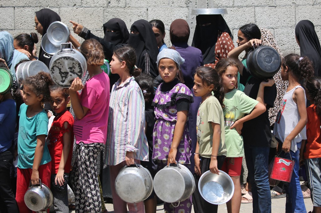 Palestinians gather to receive cooked meals from a food distribution center in the Nuseirat refugee camp in the central Gaza Strip on August 18, 2025. 
