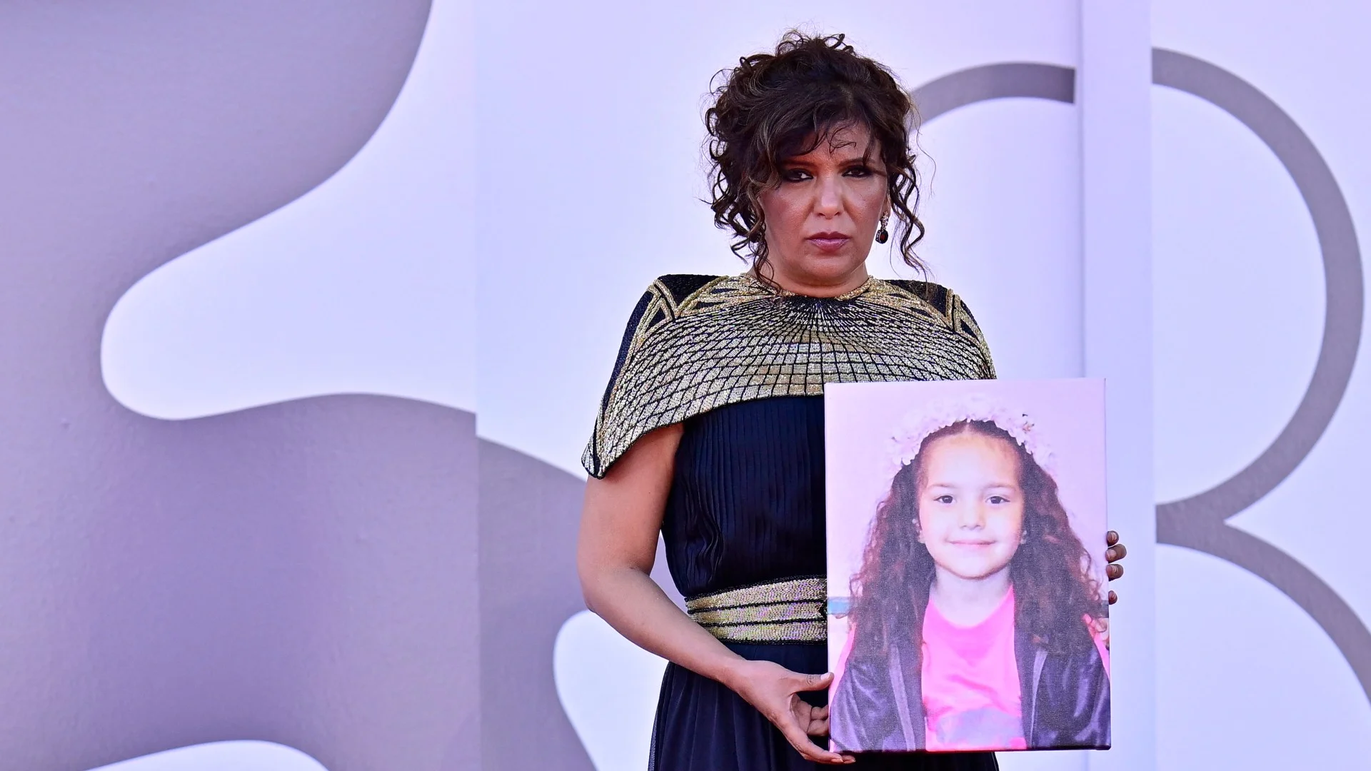 Tunisian director Kaouther Ben Hania holds a portrait of Palestinian girl Hind Rajab during the red carpet event for the movie 