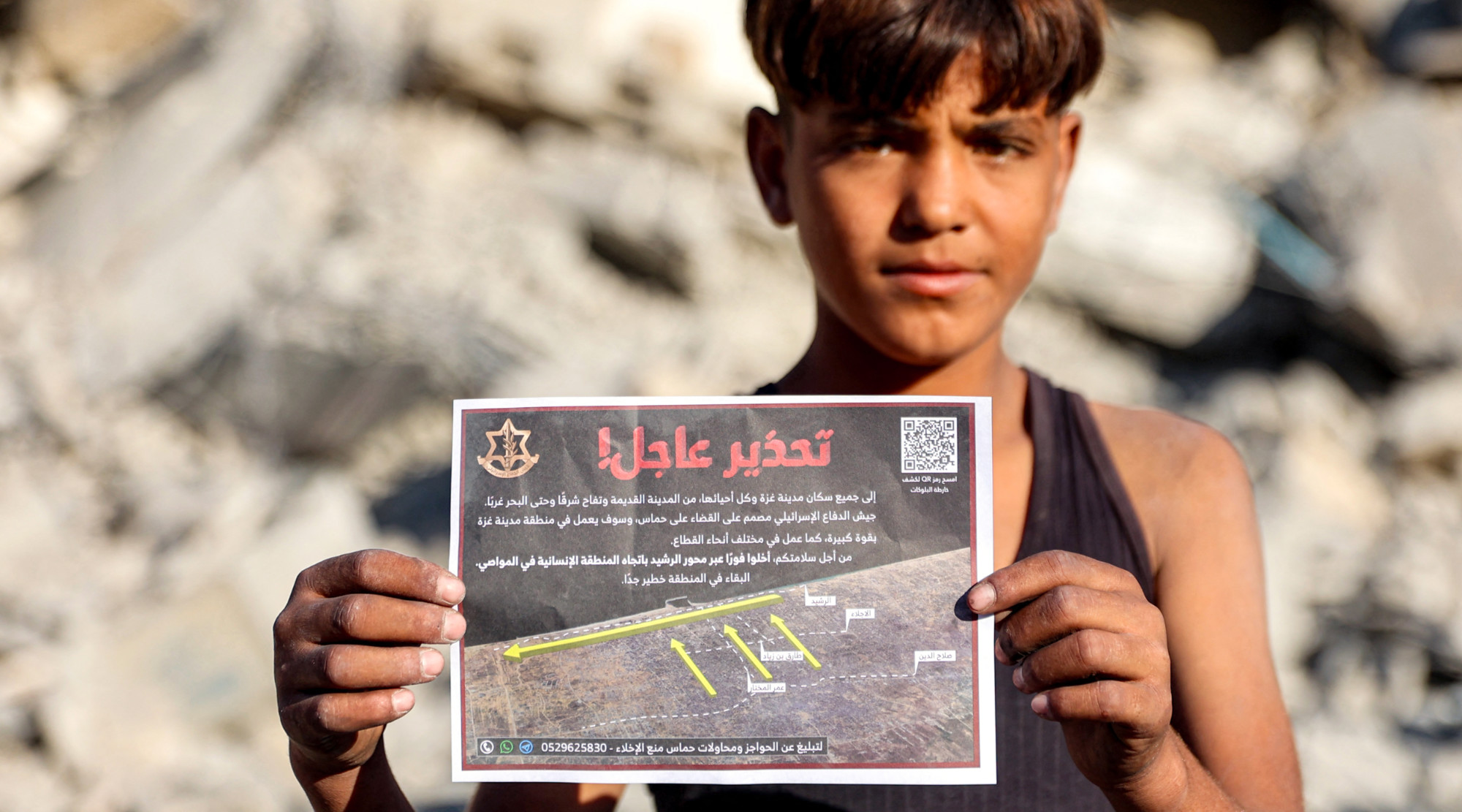 A boy holds a leaflet dropped by the Israeli military on Gaza City, urging mass expulsion to the south, on 9 September 2025 (AFP/Omar al-Qattaa)