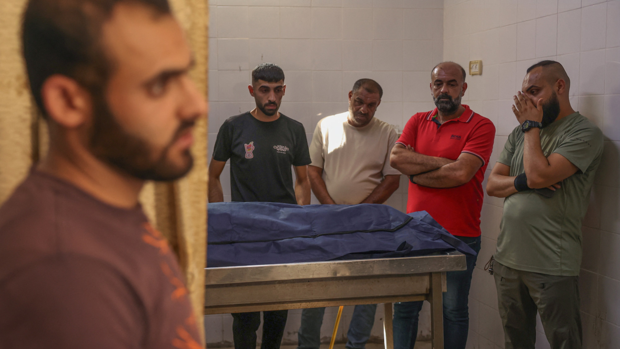 Palestinians stand next to Sanad Hantuli's body at Ramallah's government hospital after Israeli forces killed him on near the separation wall in Jerusalem on 15 September 2025 (AFP/Zain Jaafar)