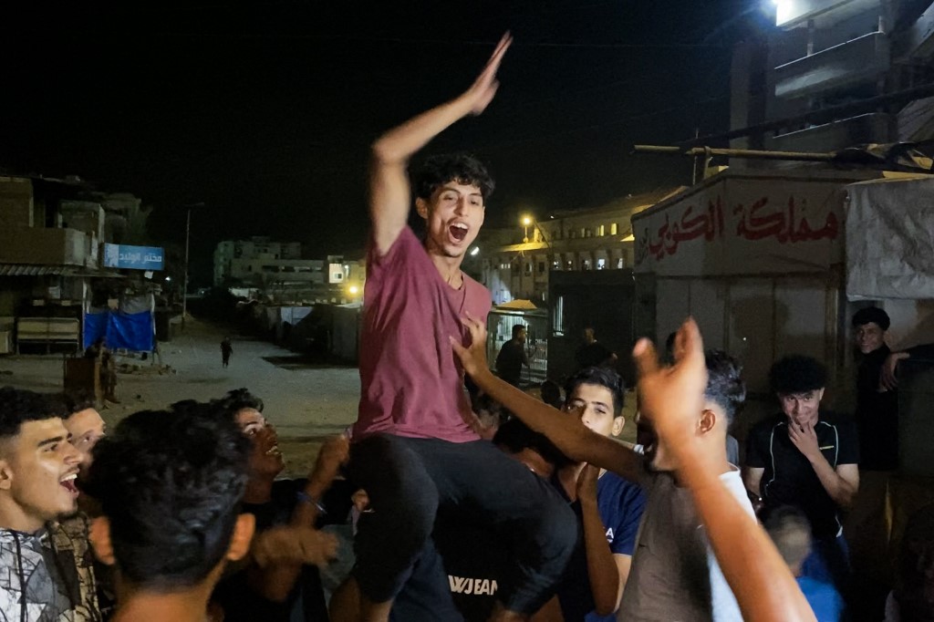 Palestinians celebrate in Khan Yunis on October 9, 2025, following news of a new Gaza ceasefire deal. US President Donald Trump announced that Israel and Hamas have agreed to the first phase of a ceasefire in Gaza, after days of indirect talks in Egypt.