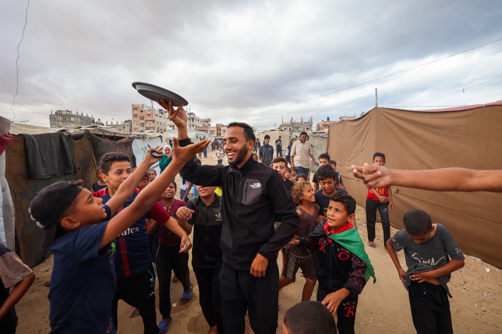 A man distributes sweets at a camp for displaced Palestinians in Nuseirat in the central Gaza Strip on October 9, 2025, 