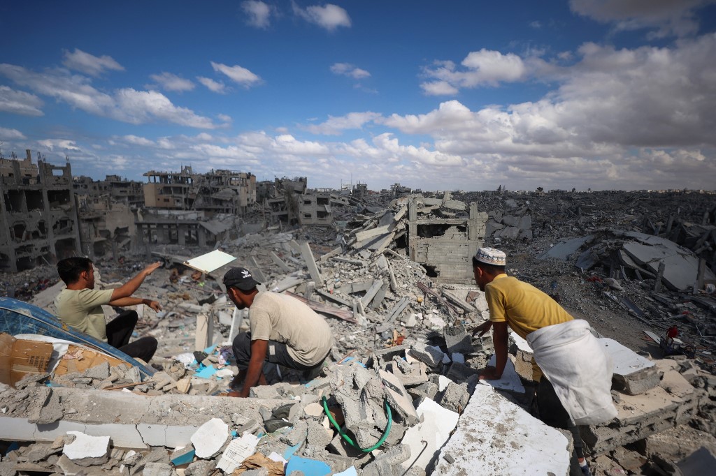 Palestinians search the rubble of buildings amid widespread destruction due to Israeli bombardment in Khan Yunis in the southern Gaza Strip, as a ceasefire holds on October 12, 2025.