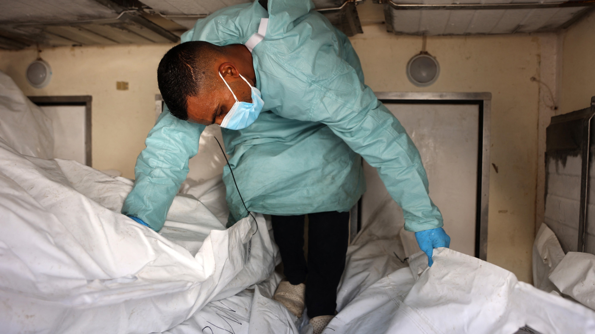 A hospital employee checks the remains of Palestinians released by Israel inside a refrigerated truck in front of the Nasser hospital in Khan Yunison 18 October 2025 (AFP/Omar al-Qattaa)