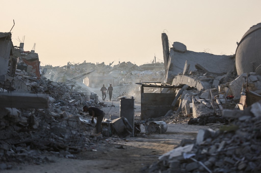 Palestinians walk amid the rubble of destroyed buildings in the Sheikh Radwan neighborhood of Gaza City on October 22, 2025. 