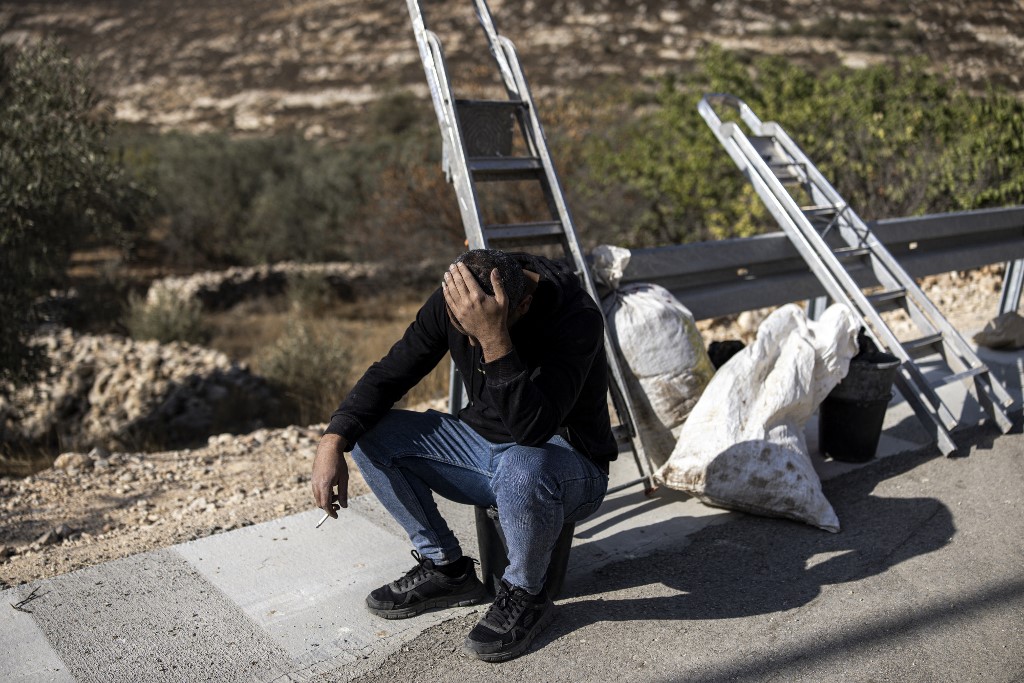 A Palestinian man sits next to his ladder after Israeli forces and settlers prevented him from harvesting olives in the Palestinian village of Sa'ir, near the Israeli occupied West Bank city of Hebron, on October 23, 2025.