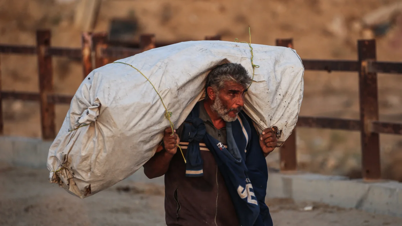 A Palestinian man carries his belongings along a bridge in Nuseirat, Gaza Strip, on 11 November 2025 (AFP/Eyad Baba)