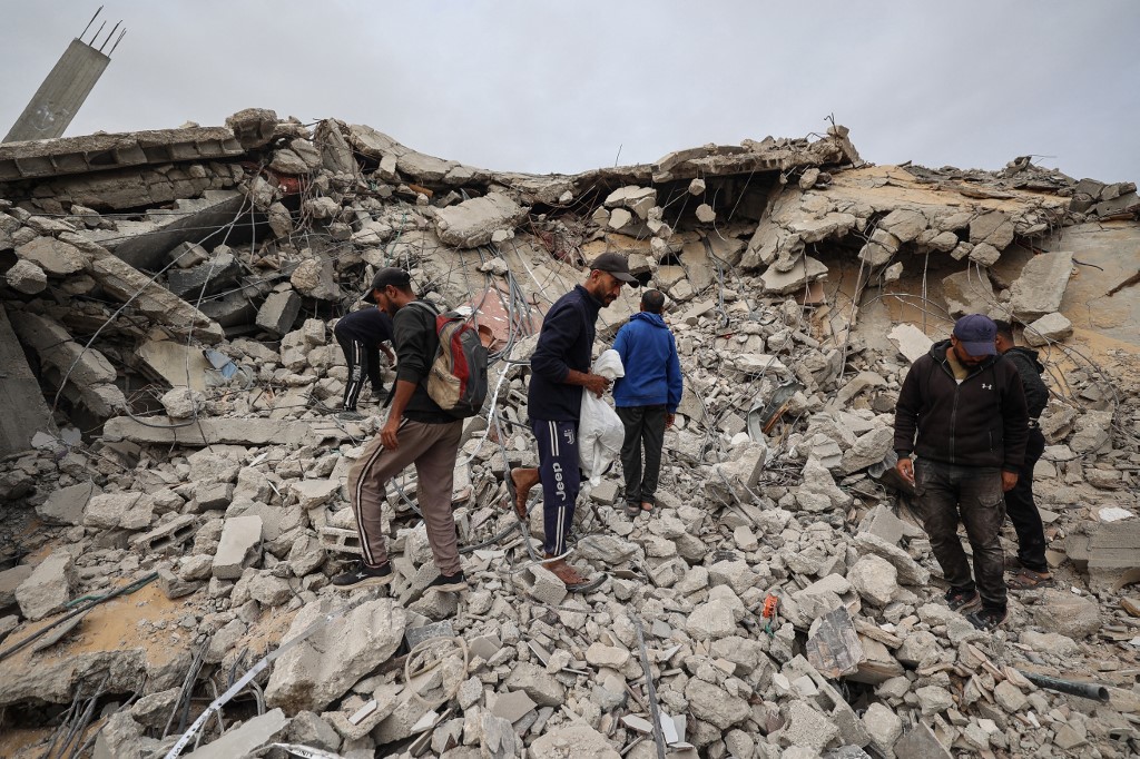 Palestinian men search the rubble of a destroyed building for the remains of victims in the Bureij refugee camp, in the central Gaza Strip, on 6 December, 2025. (AFP)
