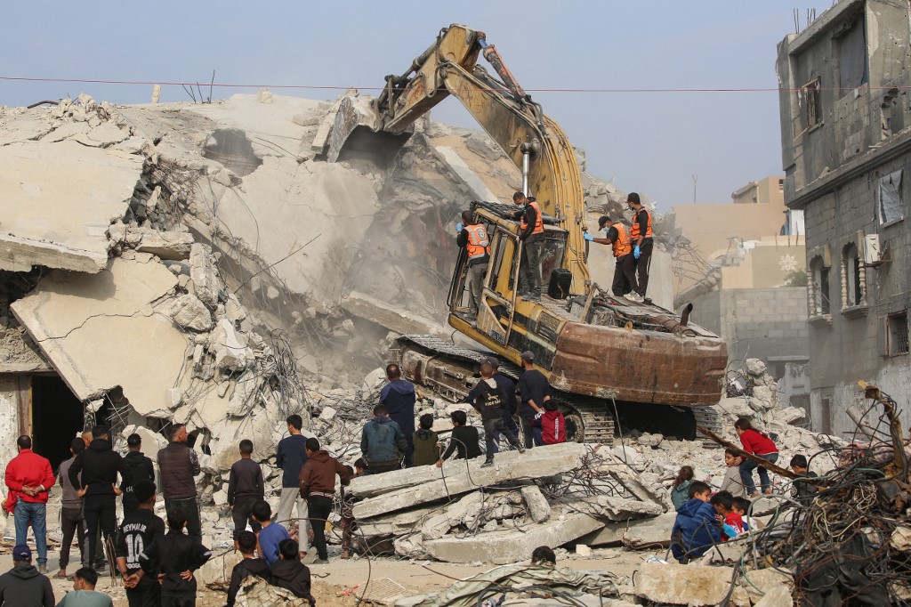 Civil Defence personnel use an excavator to search for the remains of victims in the rubble of a destroyed building in the Bureij refugee camp, in the central Gaza Strip, on 6 December, 2025. (AFP)