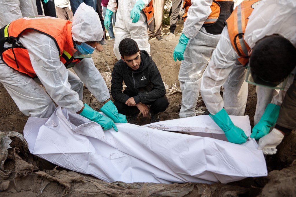 Civil defence personnel and relatives exhume graves inside the Al-Ahli Arab Baptist Hospital to transfer the remains to official burial sites in Gaza City on 7 December, 2025. (AFP)