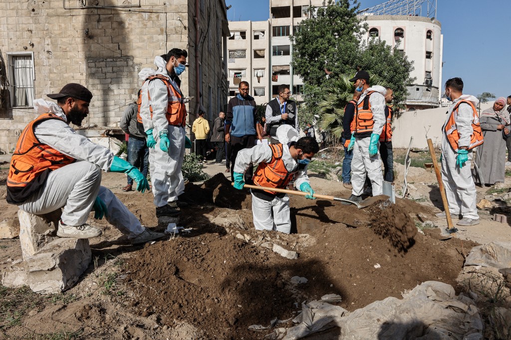 Civil defence personnel and relatives exhume graves inside the Al-Ahli Arab Baptist Hospital to transfer the remains to official burial sites in Gaza City on 7 December, 2025. (AFP)