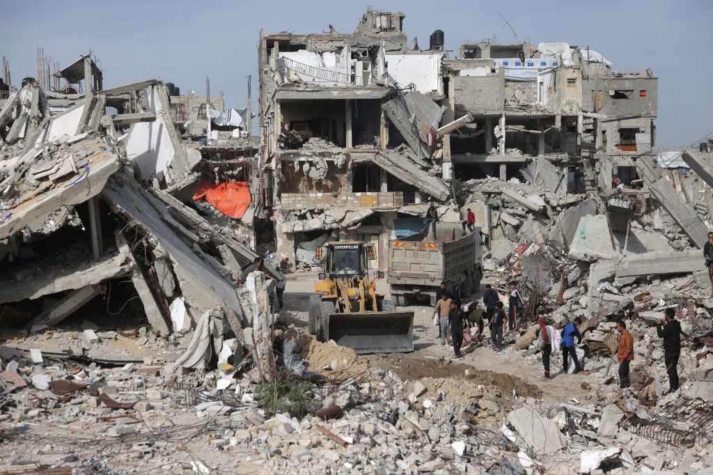 A Palestinian worker involved in a rubble management project implemented and supervised by UNDP for the Gaza Strip, manuevers a digger used to shift concrete, metal and the debris of destroyed buildings and houses as the reopening and managing of streets blocked by the rubble takes place, in Khan Yunis, in the southern Gaza Strip on December 13, 2025, 