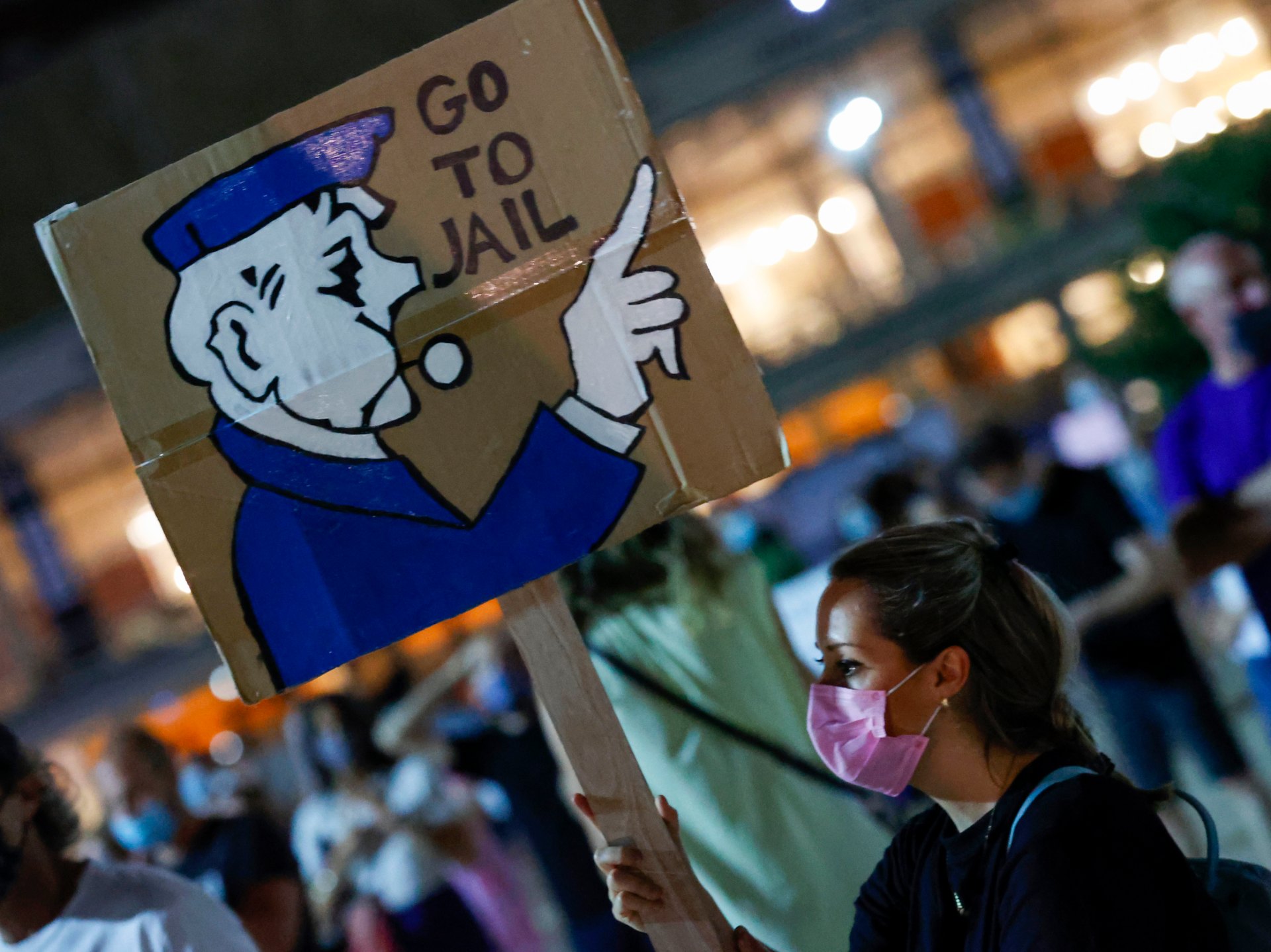 An Israeli anti-government protester carries a placard during a demonstration against Prime Minister Benjamin Netanyahu and against the second nationwide lockdown (AFP)