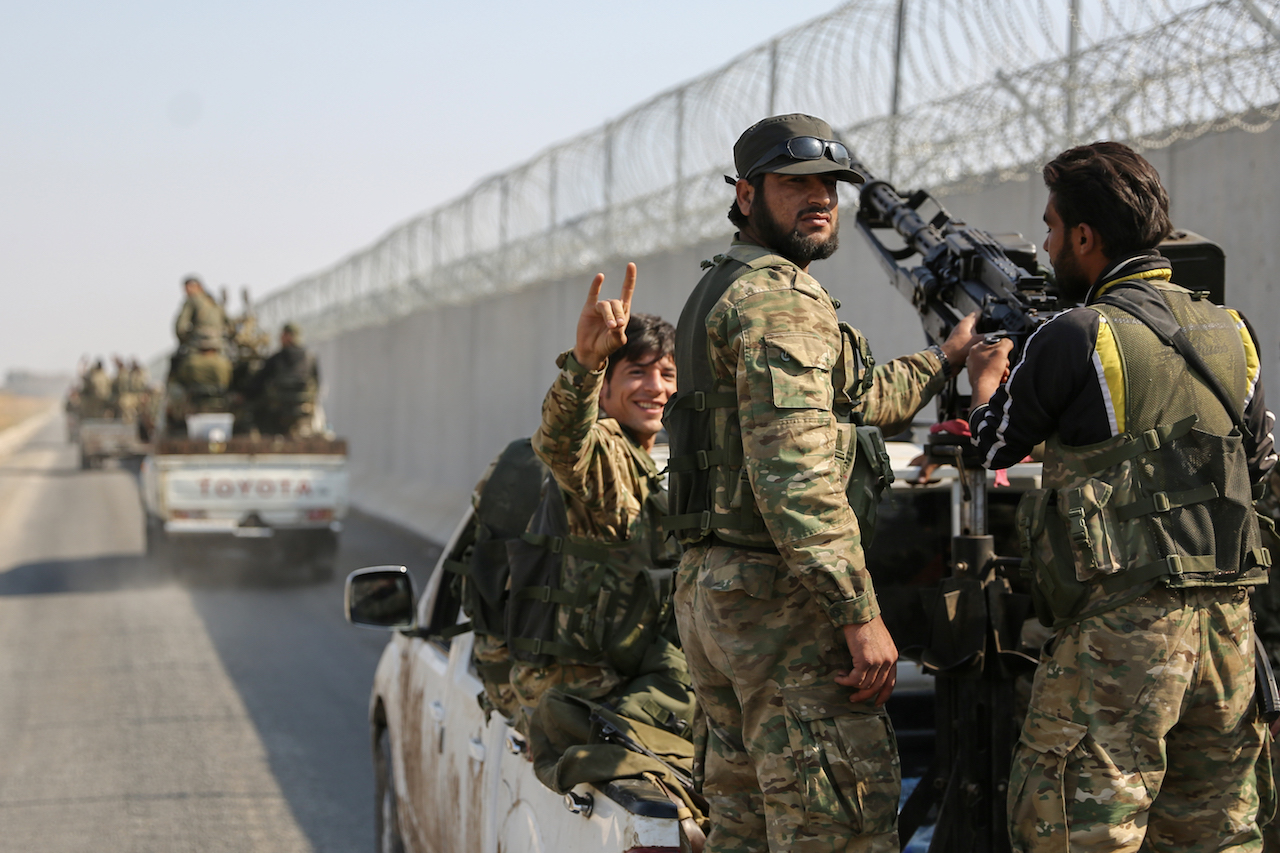 A Turkey-backed Syrian fighter flashes the Grey Wolves (a Turkish far-right ultranationalist organisation) sign as a convoy travels along the border between Syria and Turkey (AFP)