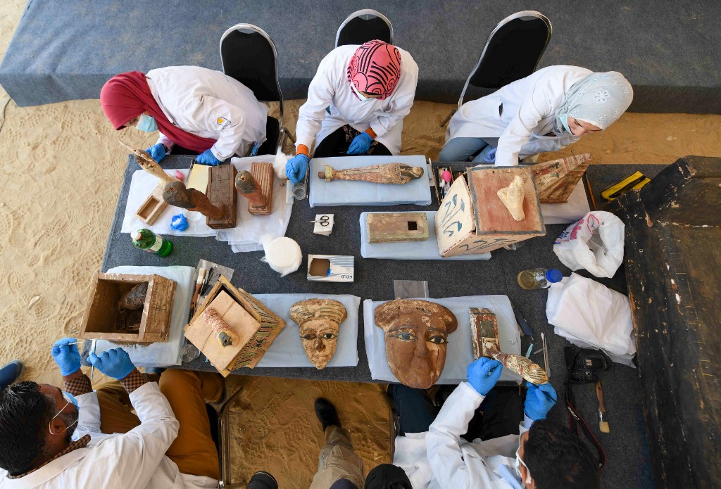 Archaeologists clean statues and funerary masks in Saqqara necropolis, south of Cairo (AFP)