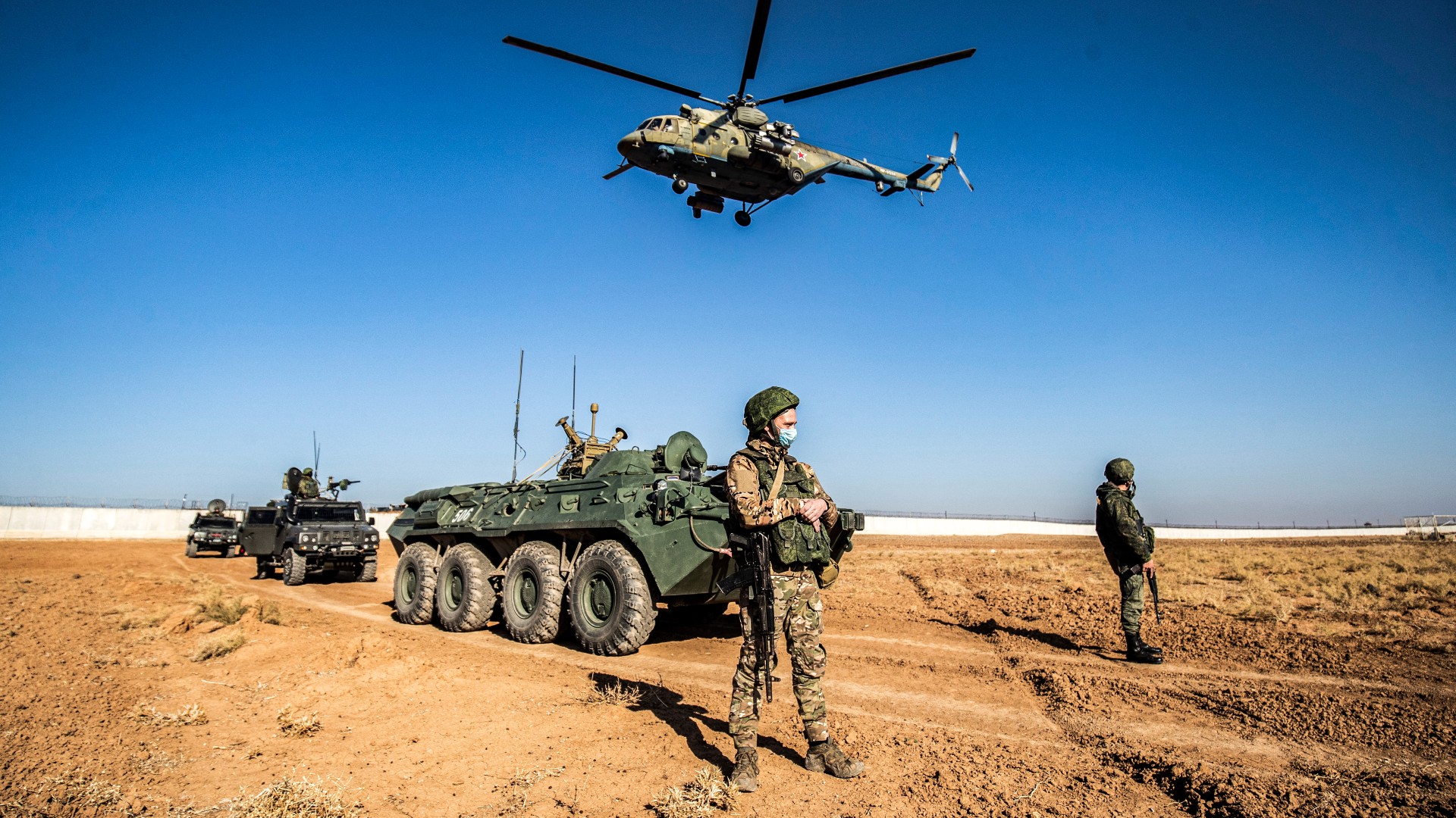 A Russian Mil Mi-17 military helicopter flies by soldiers and military vehicles during a joint Russian-Turkish patrol in the eastern countryside of Syria (AFP)
