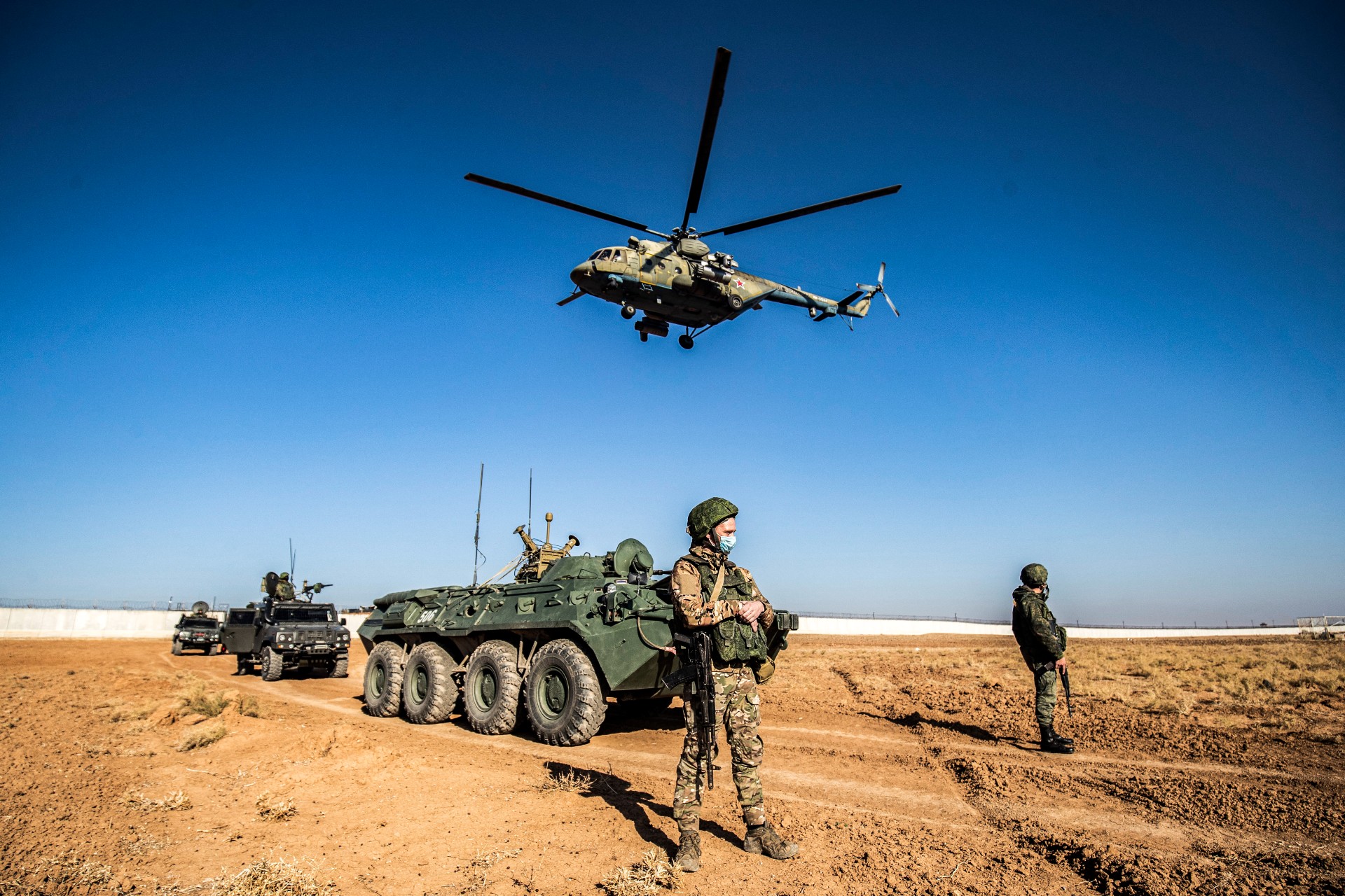 A Russian Mil Mi-17 military helicopter flies by soldiers and military vehicles during a joint Russian-Turkish patrol in Syria (AFP)