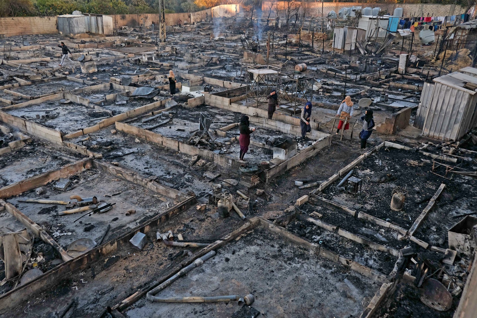 Syrian refugees salvage belongings from the wreckage of their shelters at a camp set on fire overnight in the northern Lebanese town of Bhanine on 27 December (AFP)