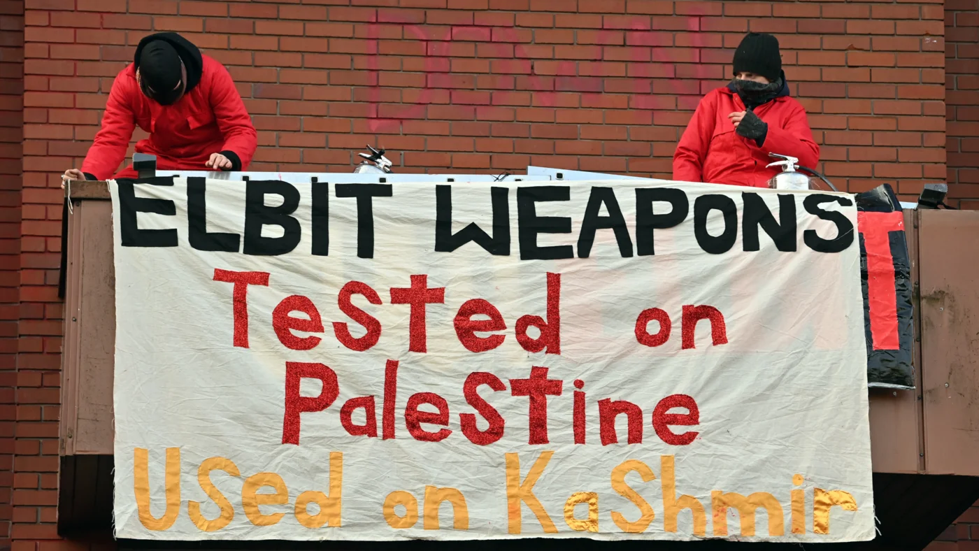 Activists fix a banner as they protest outside the Elbit Systems' Ferranti factory in Oldham, northwest England on 1 February 2021 (AFP/Paul Ellis)