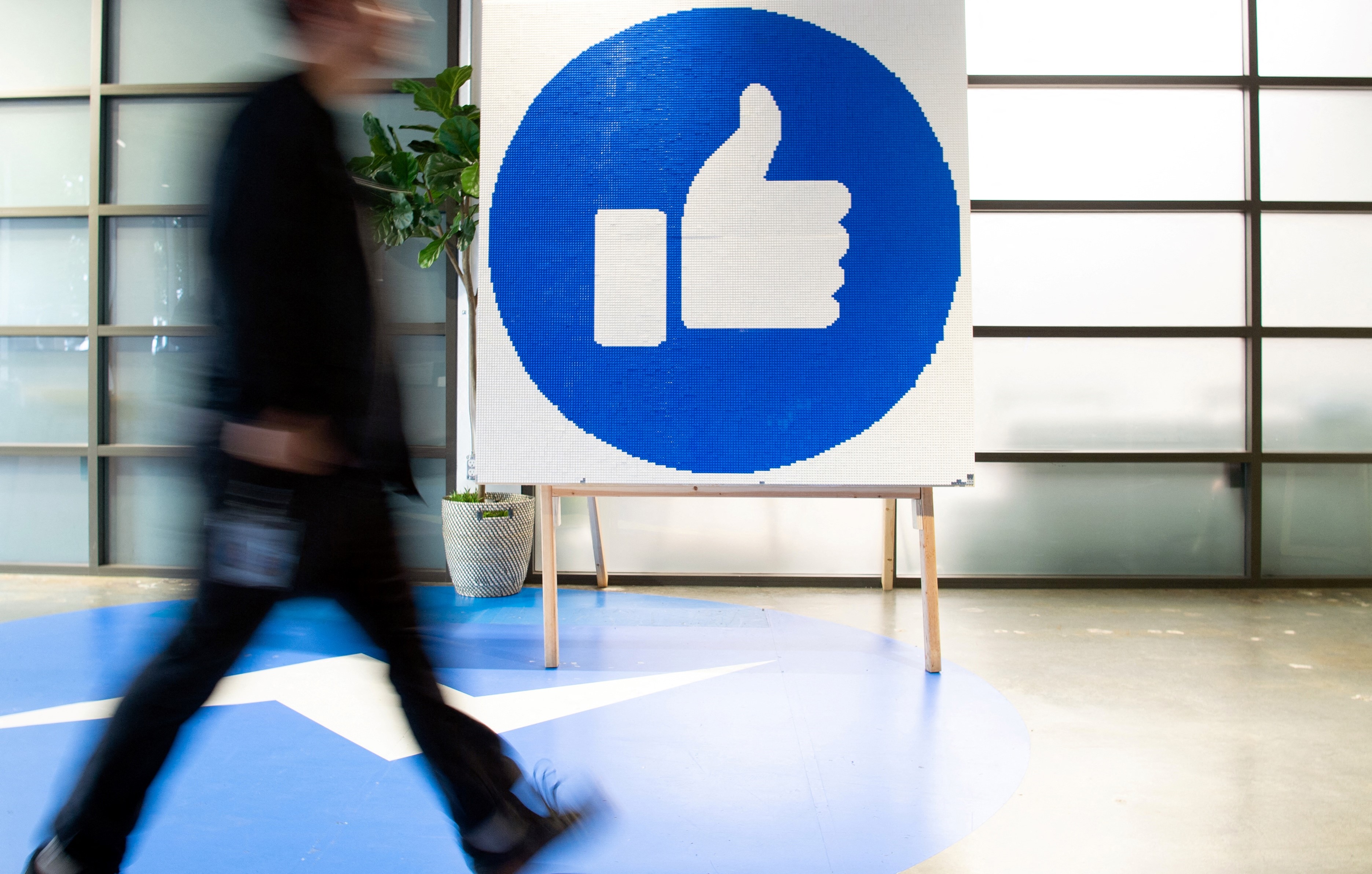 a Facebook employee walking past a sign displaying the 